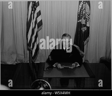 Le président Harry S. Truman assis à un bureau, devant un micro, annonçant la fin de la Seconde Guerre mondiale en Europe. Banque D'Images