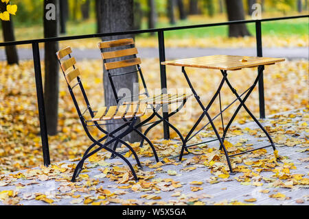 De l'automne. Table et chaises en bois dans le parc automne vide, tombée feuilles d'érable. Concept de l'humeur d'automne Banque D'Images