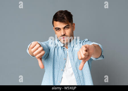 Jeune arabe grave Man Gesturing Thumbs down sur fond gris Banque D'Images