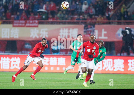 Joueur de football portugais Ricardo Vaz Te, gauche, et joueur de football camerounais Christian Bassogog, centre, de Henan Jianye passer le ballon contre playe Banque D'Images