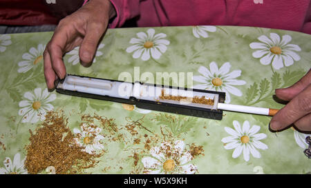 La confection de cigarettes de tabac à la main avec des rouleaux et sur une table à la maison. Banque D'Images