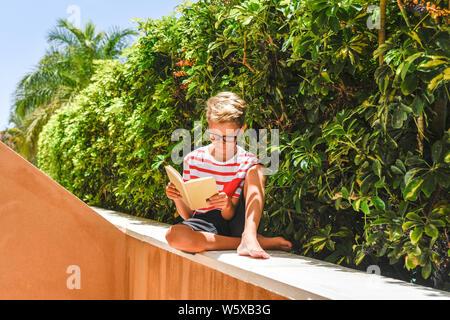 Portrait of a young woman sitting lit un livre vert sur l'extérieur couverture arrière-plan étudiant à faire leurs devoirs après l'école sur une belle journée ensoleillée Banque D'Images