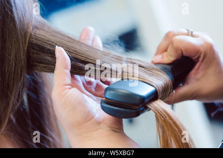 Coiffure à l'aide de fer plat sur des cheveux de femme customer Banque D'Images