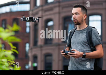 Jeune homme séduisant le lancement de drone quadcopter au contexte urbain. paysage urbain. appareil moderne. Banque D'Images