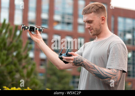 Jeune homme séduisant le lancement de drone quadcopter au contexte urbain. paysage urbain. appareil moderne. Banque D'Images