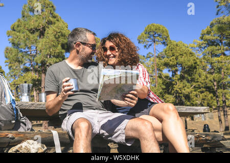 Smiling couple prendre du repos après la randonnée en l'homme et la femme à la carte pour trouver le chemin de randonnée heureux peuples caucasiens de boire du café à la Banque D'Images