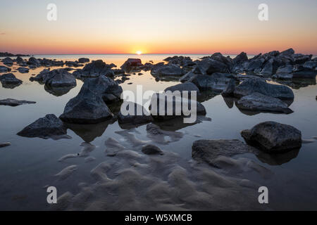 Lever de soleil au-dessus de l'horizon avec les roches qui se découpent sur la mer au large de Klintely Hotel beach, Allinge, île de Bornholm, mer Baltique, Danemark, Europe Banque D'Images