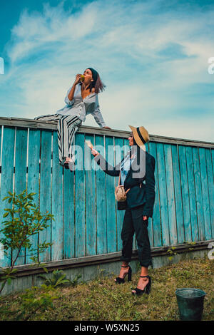 Tom Sawyer jolie femme dans le faisceau de la hat standing en face de clôture. La femme a peint une clôture en bois. Banque D'Images