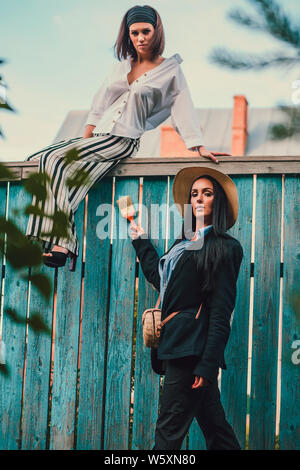 Tom Sawyer jolie femme dans le faisceau de la hat standing en face de clôture. La femme a peint une clôture en bois. Banque D'Images