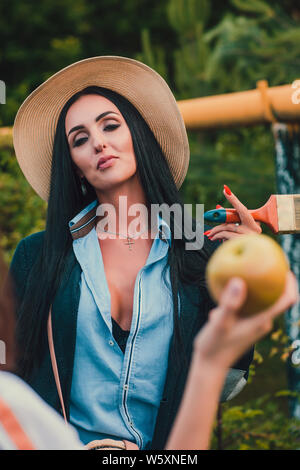 Tom Sawyer jolie femme dans le faisceau de la hat standing en face de clôture. La femme a peint une clôture en bois. Banque D'Images