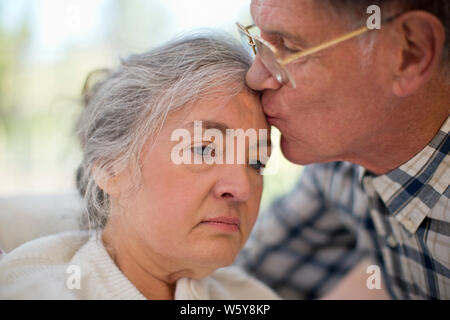 Senior femme malheureuse d'être embrassé sur le front de son mari. Banque D'Images