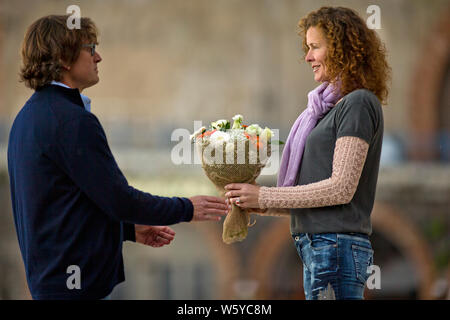 Homme d'âge moyen donnant un beau bouquet de fleurs à sa date. Banque D'Images