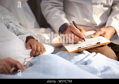 Médecin à prendre des notes lors d'un entretien avec un patient dans l'hôpital. Banque D'Images