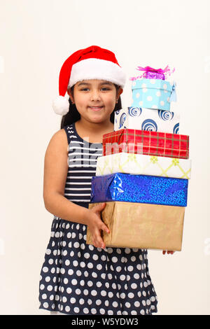 Girl holding stack of gifts and smiling Banque D'Images