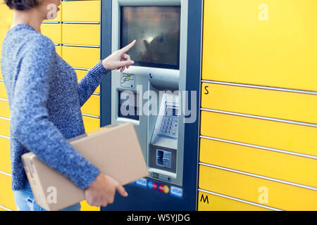 Femme client utilisant le libre-service automatisé machine terminal post ou un casier pour déposer le colis de stockage, Banque D'Images