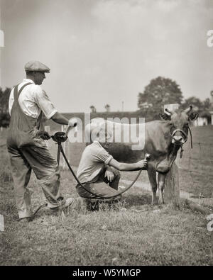 Années 20, DEUX HOMMES ANONYMES PRODUCTEURS LAITIERS À L'aide de tondeuses à main mécanique coudés à toiletter SUR LAIT DE VACHE JERSEY USA RURAL - c3822 HAR001 HARS UNITED STATES COPIE ESPACE PERSONNES vache pleine longueur BRETELLES UNITED STATES OF AMERICA s'occuper des mâles d'AGRICULTURE AGRICULTURE PROFESSION B&W AMÉRIQUE DU NORD-AMÉRICAIN DES BOVINS DE TOILETTAGE OCCUPATION COMPÉTENCES CARRIÈRES COMPÉTENCES CONNAISSANCES LES AGRICULTEURS DE L'INNOVATION À L'AIDE DE VACHES PROFESSIONS CONCEPTUEL ANONYME ÉLÉGANT MAMMIFÈRE CLIPPERS MID-ADULT MAN MI-NOIR ET BLANC DE L'ORIGINE ETHNIQUE CAUCASIENNE HAR001 domestiqués à l'ancienne de l'élevage Banque D'Images