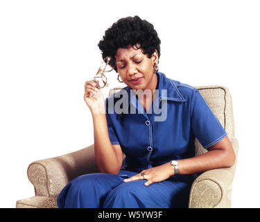 1970 Africains-Américains femme assise DANS UN FAUTEUIL HOLDING EYEGLASSES contre sa tempe souffrant d'un mal de tête ou d'une affection douloureuse - ks13604 HAR001 HARS COPIE ESPACE CONTRE DEMI-LONGUEUR MESDAMES LES PERSONNES QUI S'OCCUPENT Mal de tête lunettes soins de tristesse EN DIFFICULTÉ PRÉVENTION SOUFFRANCE TEMPLE HIGH ANGLE HEALING africains-américains africains-américains NOIR ORIGINE DIAGNOSTIC SÉVÈRE DE LA SANTÉ TRAITEMENT DE L'humeur morose conceptuelle tenue détente élégant FACILE OU UNE MAUVAISE SANTÉ MAUVAISE MID-ADULT WOMAN FEMME BLEU MARINE PANTALON misérable douloureuse maladie CONVIENNENT HAR001 MIGRAINE OLD FASHIONED AMÉRICAINS AFRICAINS Banque D'Images