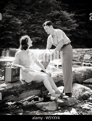 1940 JEUNE COUPLE À CÔTÉ D'UN RUISSEAU SUR SUMMER DAY WOMAN SITTING ON LOG REPOSANT SUR LE BRAS DE PORTABLE RADIO MAN UNE JAMBE VERS LE HAUT SUR LOG - r6237 HAR001 HARS STRONG JOIE SON MODE DE VIE SANTÉ FEMELLES COPIE ESPACE NATURE PLEINE LONGUEUR D'AMITIÉ CHERS PERSONNES INSPIRATION pittoresque ruisseau s'occupent les hommes PORTABLE DIVERTISSEMENT B&W L'ÉTÉ AU REPOS DATING BONHEUR BRUNETTE RADIODIFFUSION RADIOS JOURNAL LOISIRS LOISIRS AUDIO PANTALON ATTRACTION DE FRÉQUENTATIONS RELATIONS OXFORD SELLE À CÔTÉ ATTACHEMENT PERSONNEL ÉLÉGANT POSSIBILITÉ D'AFFECTION DE L'émotion de l'activité sociale solidarité jeune adulte HOMME NOIR ET BLANC Banque D'Images