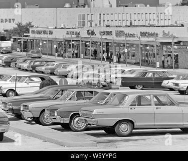 1970 VARIÉTÉ DE VOITURES CONFITURE EMBALLÉE DANS UN CENTRE COMMERCIAL CENTRE COMMERCIAL STATIONNEMENT PIÉTONS ET SHOPPERS MARCHER PAR STORE FRONTS - s17107 HAR001 HARS VÉHICULES DIVERS ÉPICERIE SHOPPING CENTRE STORE FRONTS STRIP MALL COIFFURE CROISSANCE PET STORE MAGASIN DE JOUETS HAR001 NOIR ET BLANC PARKING À L'ANCIENNE Banque D'Images