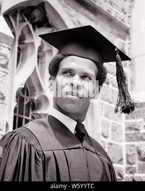 1970 AFRICAN-AMERICAN HIGH SCHOOL GRADUATE WEARING CAP AND GOWN - s18239 HAR001 LEADERSHIP CONNAISSANCES HARS LOW ANGLE NOIR ORIGINE PRIDE OCCASION ÉCOLE ENSEIGNEMENT SUPÉRIEUR COLLÈGES CONCEPTUEL CROISSANCE MORTIER YOUNG ADULT MAN NOIR ET BLANC CAP AND GOWN HAR001 old fashioned américains africains Banque D'Images