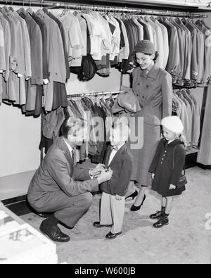 1950 Vendeur aider petit garçon ESSAYER SUR UNE VESTE ALORS QUE SA MÈRE ET SA SOEUR SOURIRE REGARDEZ SUR - s7004 HAR001 LOOK VESTE INTÉRIEUR HARS PAIRE NOSTALGIQUE 4 mères urbaines de banlieue VIEUX TEMPS NOSTALGIE FRÈRE SOEUR 1 OLD FASHION STYLE JUVÉNILE JEUNE ADULTE HEUREUX FAMILLE JOIE DE SATISFACTION DE VIE DES FRÈRES DE L'ESPACE FEMMES COPIE pleine longueur, mi-longueur CHERS FRÈRES ET SŒURS DE PERSONNES MÂLES BOUTIQUES SŒURS CONFIANCE B&W SHOPPER SHOPPING costume et cravate DE VENDRE LE BONHEUR JOYEUX SON SERVICE CLIENT ET DE CHOIX SUR LES PROFESSIONS ESSAYER SŒUR SOURIRE JOYEUX CONNEXION MAGASINS COMMERCE Noeud papillon élégant Banque D'Images