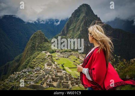 Woman traveler touristique avec sa robe rouge qui envisagent de Machu Picchu à Cusco, Pérou Banque D'Images