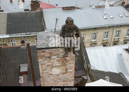 Drôle de sculpture de ramoneur pour jeter des pièces de monnaie au-dessus des toits de Lviv, Ukraine. Banque D'Images