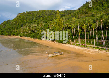 Vue aérienne d'un petit bateau en bois sur une plage à marée basse sur une île tropicale dans le soleil de fin de soirée Banque D'Images