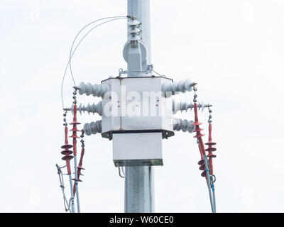 Transformateur de distribution triphasé moderne sur un poteau électrique à haute tension. Fond de Ciel blanc Banque D'Images