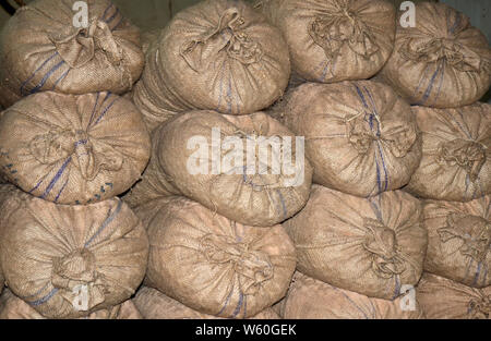 Les extrémités des sacs de toile naturel marron avec une bande bleue, pourpre, plein, rond, liés avec de la ficelle et empilées les unes sur les autres prêts pour shipp Banque D'Images