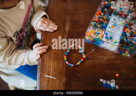 Young Girl making bracelet coloré à la maison Banque D'Images