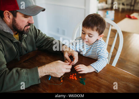 Aider les jeunes père boy making bracelet avec perles poney Banque D'Images