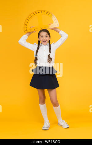 Quel angle vous regardez. classe de la tige. Mathématiques Sciences. retour à l'école. L'enseignement des mathématiques. Kid en uniforme sur fond jaune. bonne petite fille de l'école d'étudier la géométrie. élèves règle rapporteur. Banque D'Images