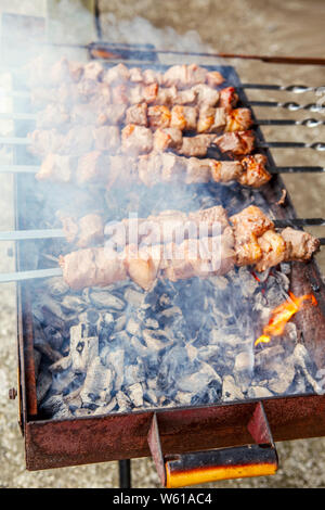 Macro closeup de matières premières de viande marinée grillée shish kebab barbecue Brochettes brochettes métalliques sur l'acier couché grill fire brazier avec charbon de bois. Banque D'Images