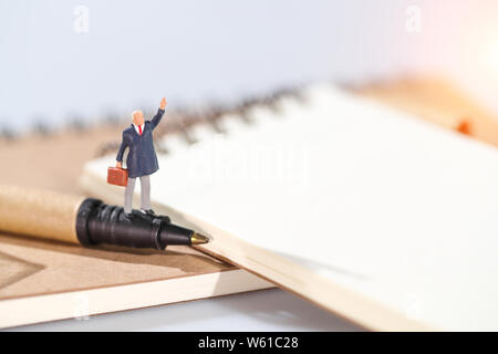 Les gens miniature : businessman standing on blank notebook idée de but d'affaires et financiers Banque D'Images