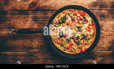 La Frittata avec brocoli et poivron rouge en fonte poêlon Banque D'Images