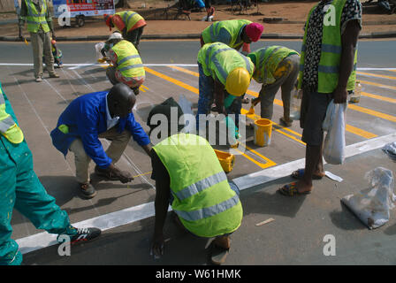 Repeindre les travailleurs de la route passage piétons bandes sur la surface de la route, Lilongwe, Malawi, Afrique. Banque D'Images