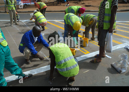 Repeindre les travailleurs de la route passage piétons bandes sur la surface de la route, Lilongwe, Malawi, Afrique. Banque D'Images