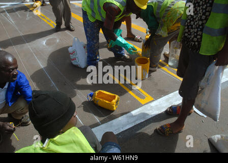 Repeindre les travailleurs de la route passage piétons bandes sur la surface de la route, Lilongwe, Malawi, Afrique. Banque D'Images