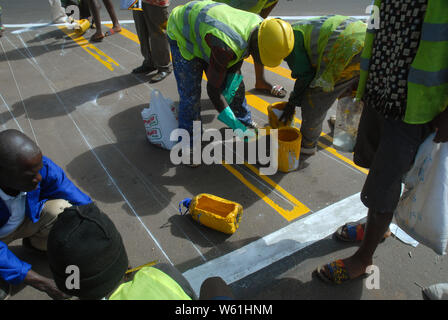 Repeindre les travailleurs de la route passage piétons bandes sur la surface de la route, Lilongwe, Malawi, Afrique. Banque D'Images