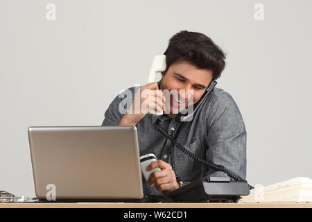 Businessman talking on landline phones and smiling Stock Photo