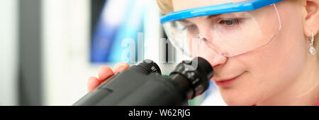 Femme scientifique à la recherche d'un microscope de laboratoire Banque D'Images