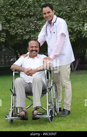 Homme souriant sur un fauteuil roulant avec un médecin Banque D'Images