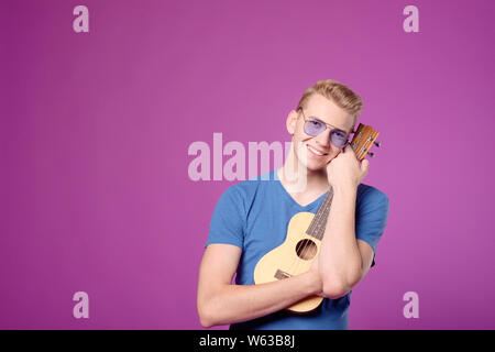 Man hugging guitar ukulele sur fond violet Banque D'Images