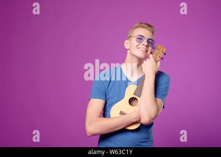 Man hugging guitar ukulele sur fond violet Banque D'Images