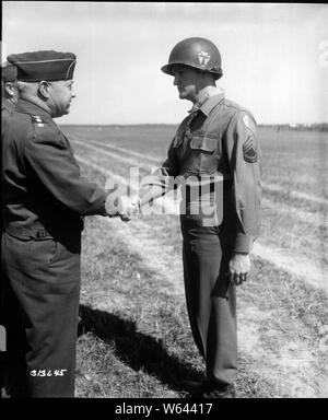 T/Sgt. Charles H. Coolidge, Signal Mountain, Tenn., membre du Co. M 141e d'infanterie, d'infanterie 36e Corps d'armée VI, septième, est félicité par le Lt Gen H. Wade Haislip, CG 7e Armée US, après qu'il a reçu la médaille d'honneur du Congrès, pour service méritoire dans la tête d'une section de mitrailleurs qui ont pris et tenu une position à l'est de Belmont sur Bruyères, France jusqu'à ce qu'il était évident que la position ne peut plus être défendue, et en attendant l'article couverts, le flanc droit du 3e Bn. et soutenu son action. 18 juin 1945. Dornandt, Allemagne. Banque D'Images