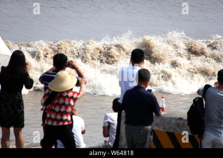 Les visiteurs et les résidents watch ondes d'un mascaret de rivière Qiantang jaillissant sur la rive du fleuve à Haining City, Zhejiang en Chine est de bauvin Banque D'Images