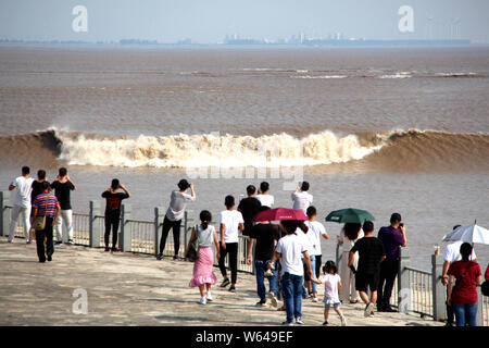 Les visiteurs et les résidents watch ondes d'un mascaret de rivière Qiantang jaillissant sur la rive du fleuve à Haining City, Zhejiang en Chine est de bauvin Banque D'Images