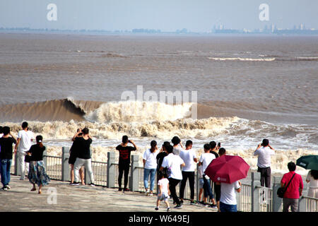 Les visiteurs et les résidents watch ondes d'un mascaret de rivière Qiantang jaillissant sur la rive du fleuve à Haining City, Zhejiang en Chine est de bauvin Banque D'Images