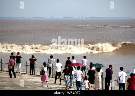 Les visiteurs et les résidents watch ondes d'un mascaret de rivière Qiantang jaillissant sur la rive du fleuve à Haining City, Zhejiang en Chine est de bauvin Banque D'Images